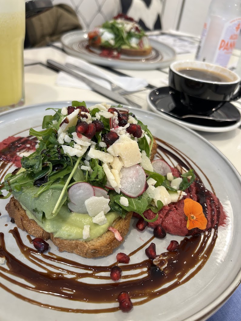 Avocado toast with rocket, pomegranate, shaved cheese and edible flowers